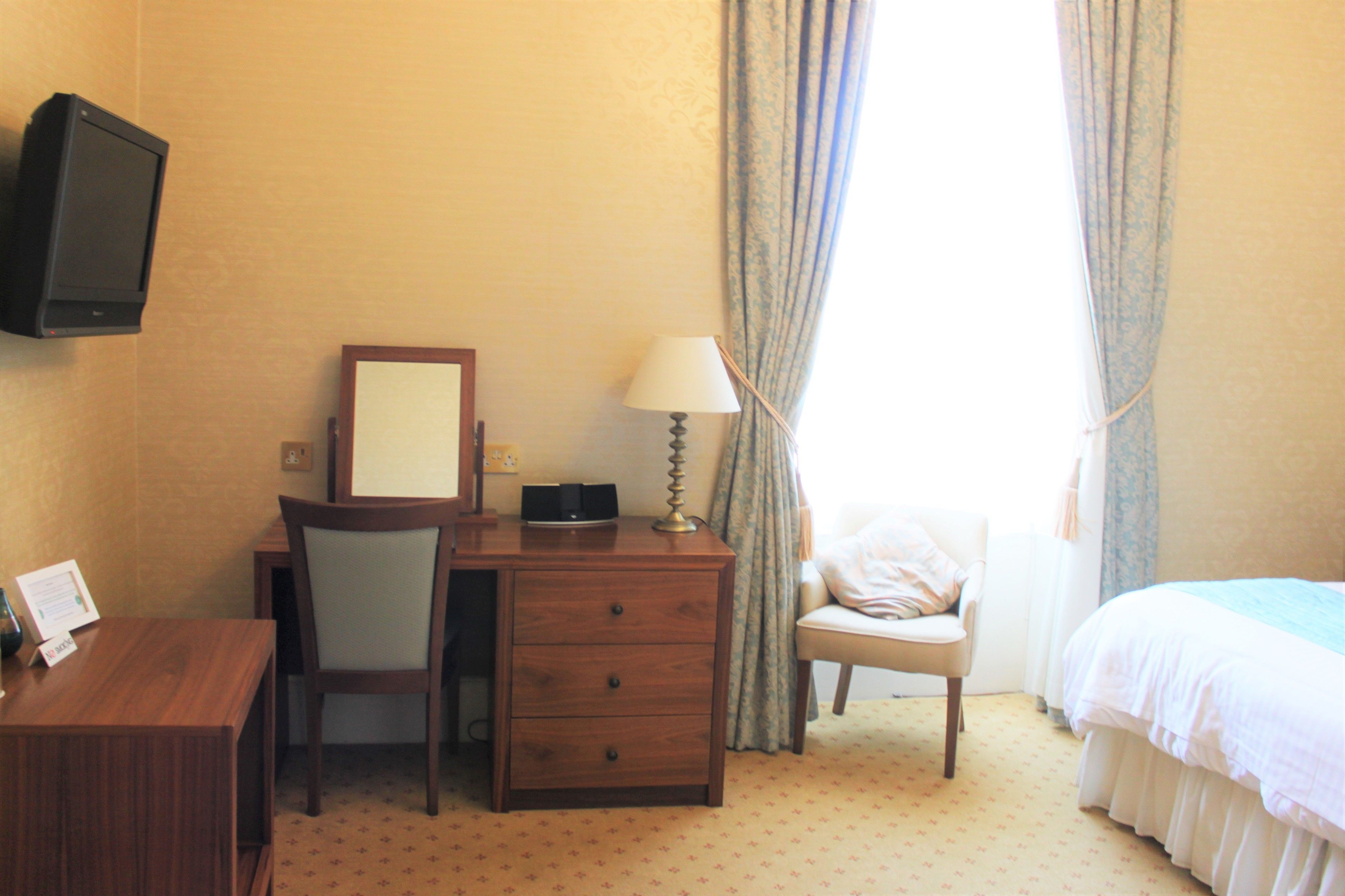 A hotel room with a wooden desk, chair, and a bed.