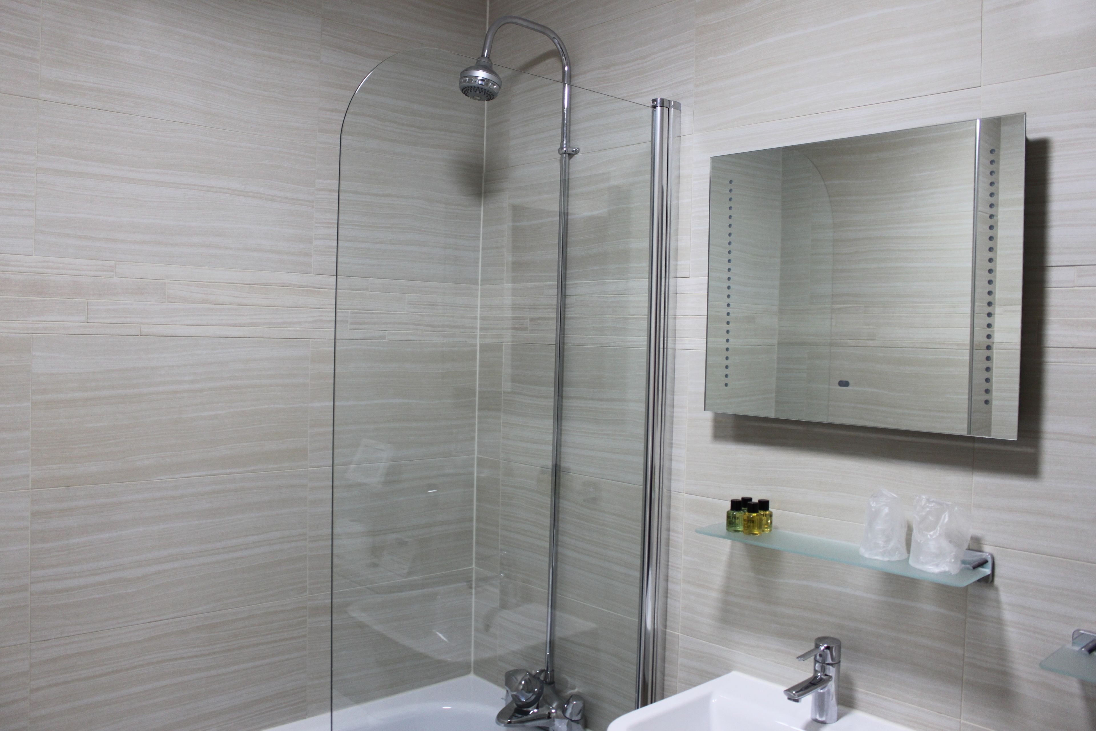 Une salle de bain moderne avec une douche à parois de verre, un lavabo et un miroir.