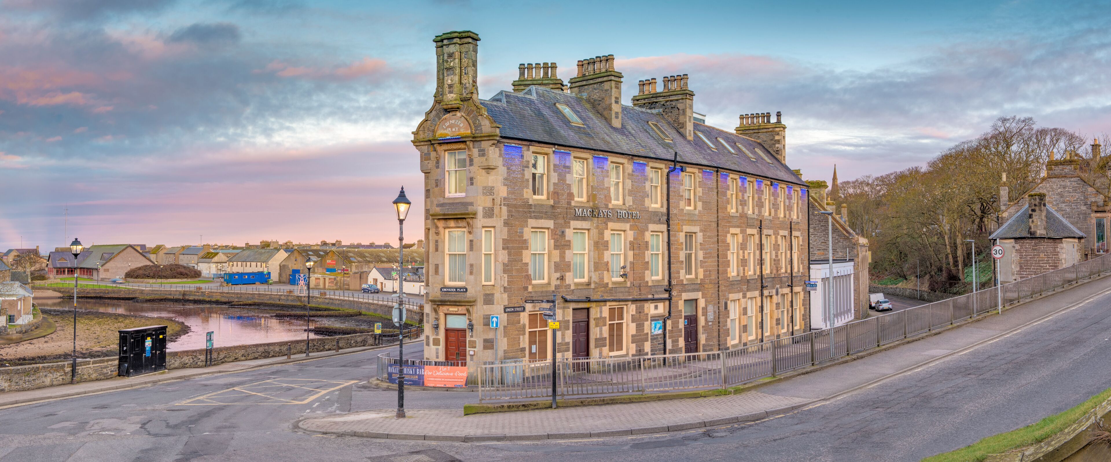 A historic building with a stone facade, multiple chimneys, and a sign reading "Mackays Hotel".