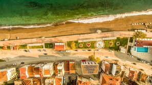 An aerial view of a coastal town with a beach, a parking lot, and a building with a sign reading "Akçakoca Poyraz Otel".