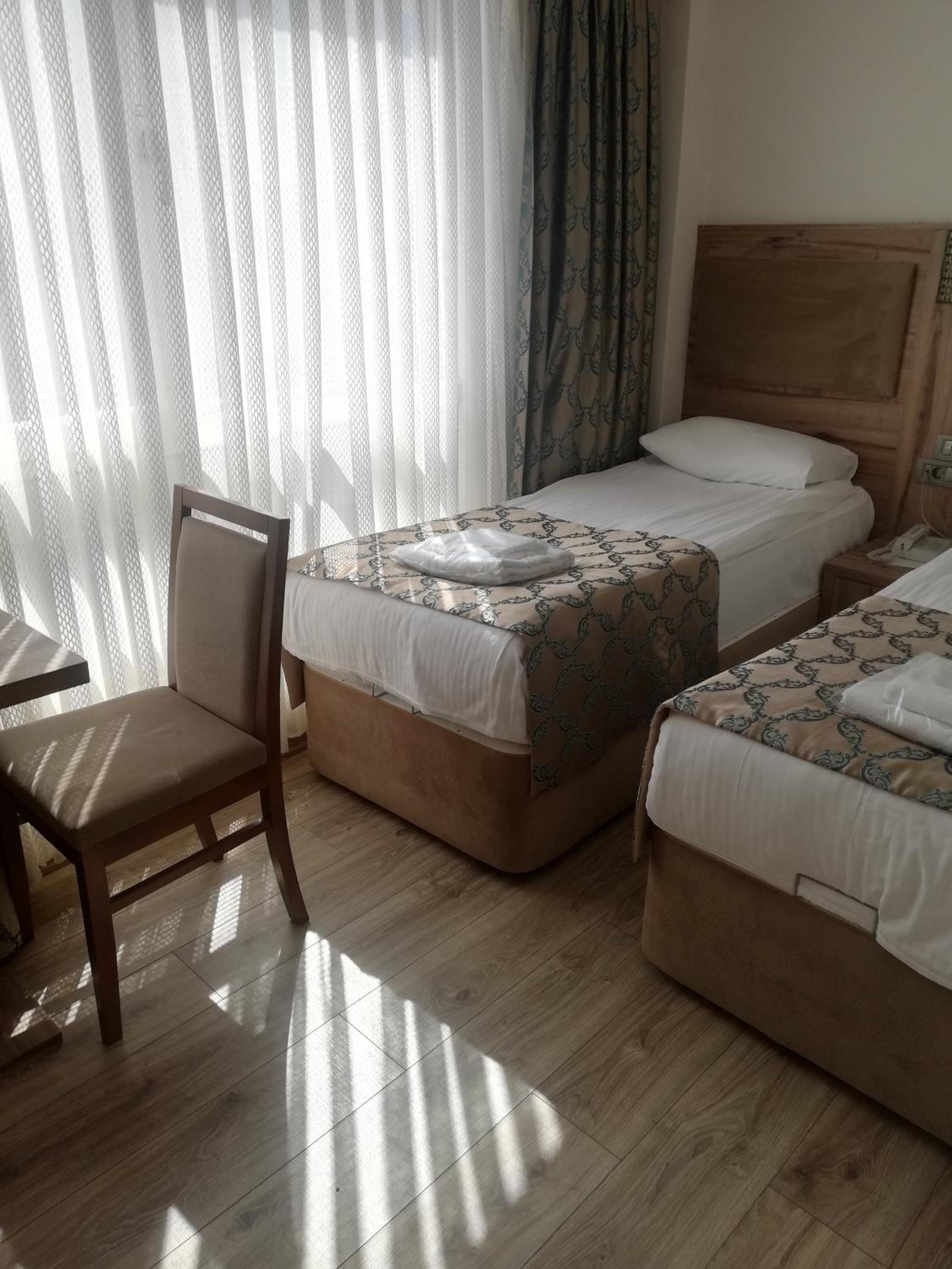 Une chambre d’hôtel avec deux lits, une tête de lit en bois, une chaise et une table.