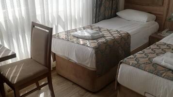 A hotel room with two beds, a wooden headboard, a chair, and a table.