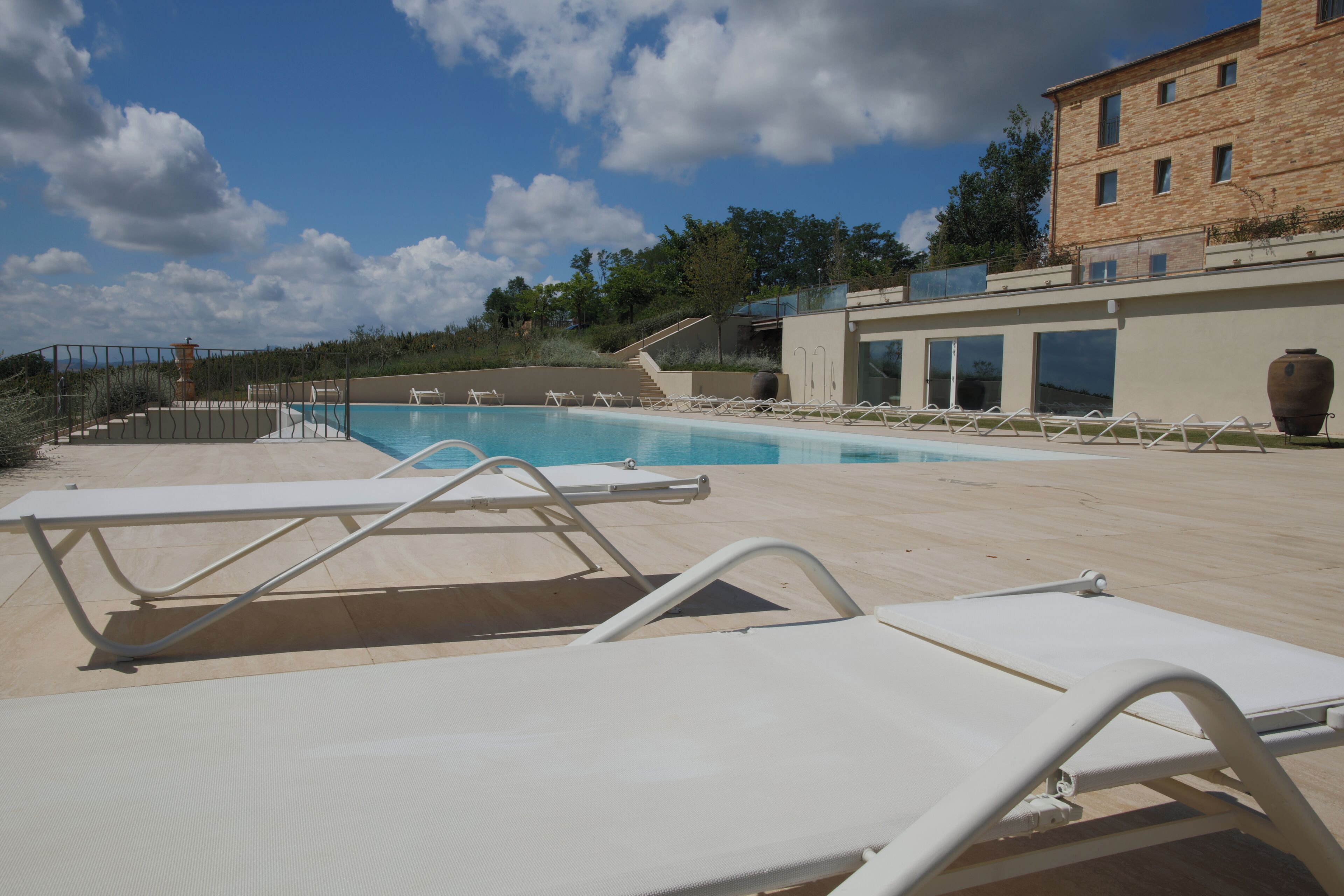 A pool area with white lounge chairs and a clear blue sky.