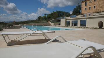 A pool area with white lounge chairs and a clear blue sky.