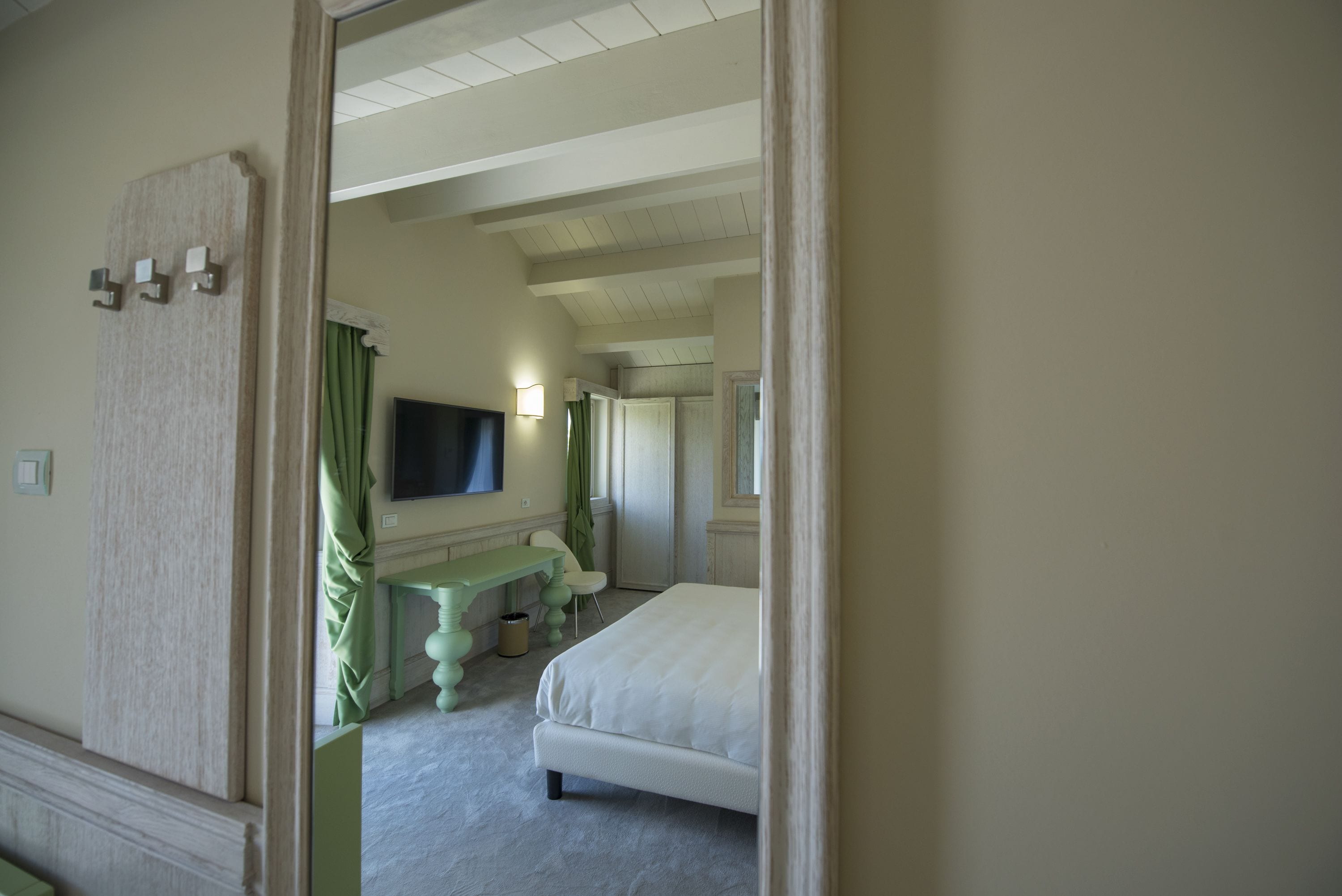 Une chambre d’hôtel équipée d’un lit, d’un bureau, d’une chaise, d’une télévision et d’un miroir.