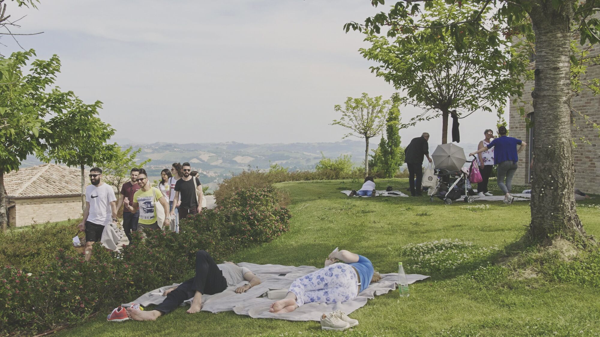 Un grupo de personas descansando en un área verde con vistas a colinas distantes.