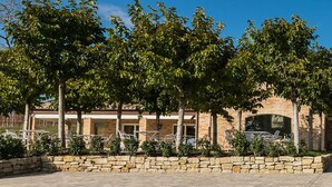 A two-story building with a stone facade, a covered outdoor seating area, and a stone pathway leading to the entrance. - Officina del Sole (Montegiorgio)