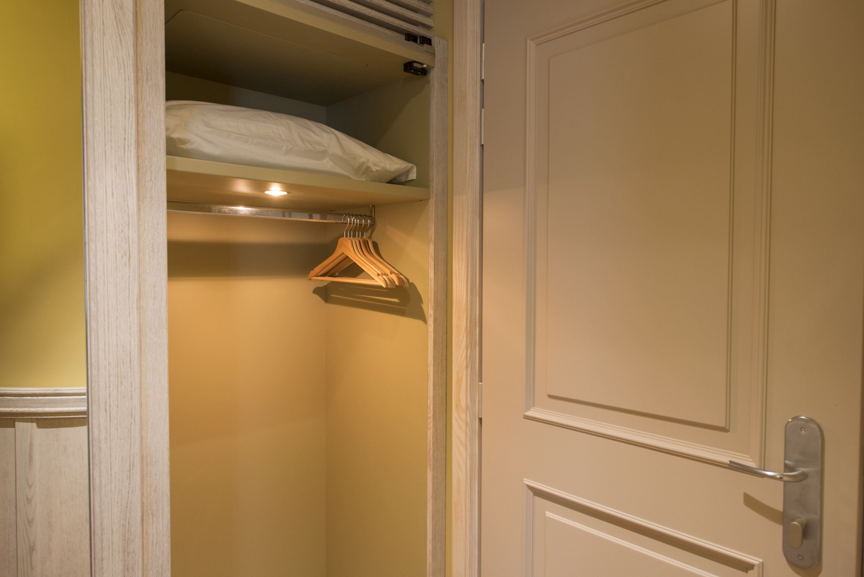 Un placard avec une tringle pour suspendre les vêtements et une porte dotée d’une poignée.