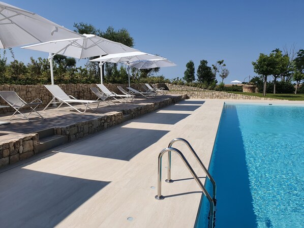 Una piscina al aire libre de temporada, sombrillas