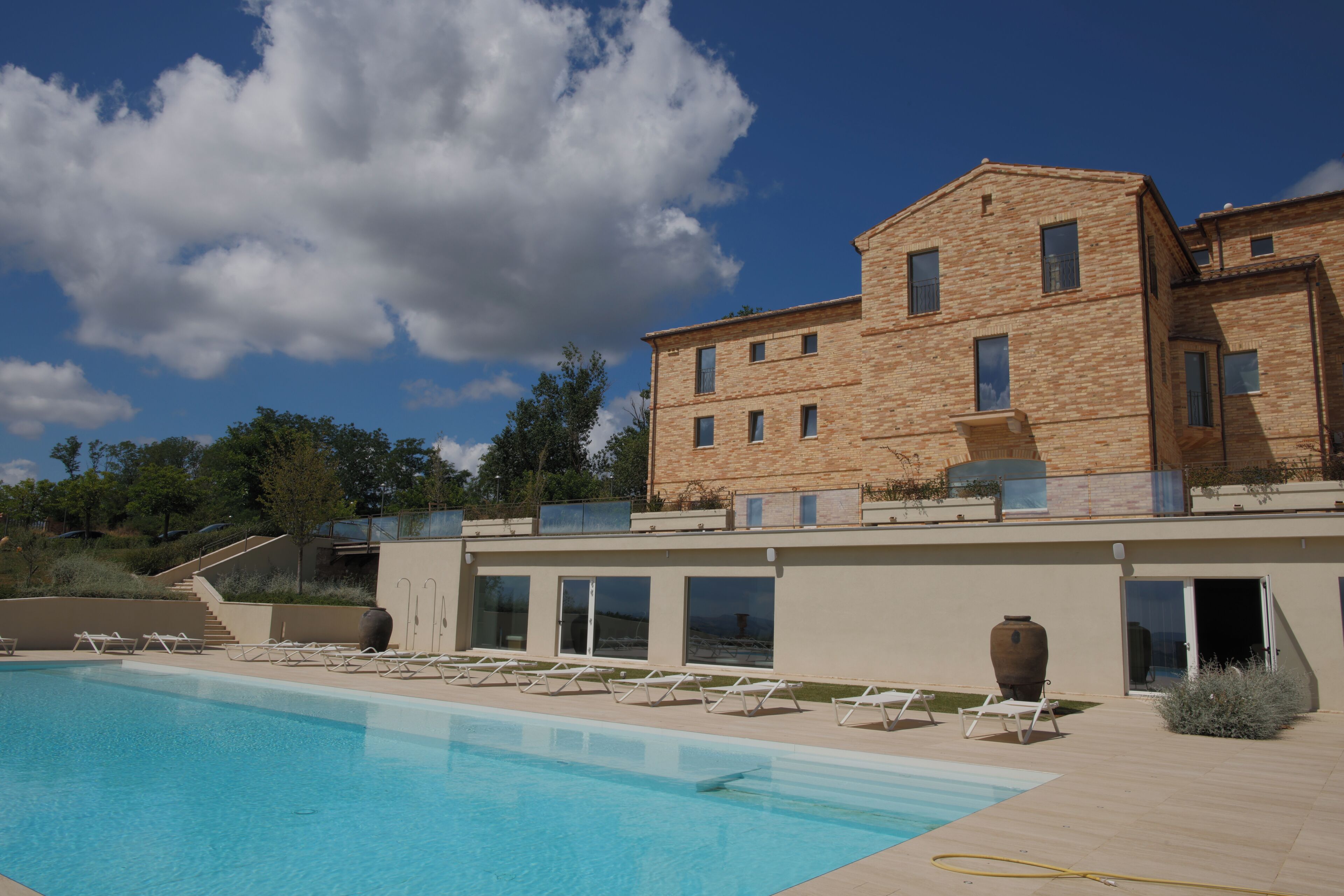 A pool area with lounge chairs, a large building with multiple windows, and a clear sky.