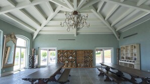 A spacious room with high ceilings, wooden benches, a chandelier, and wine racks. - Officina del Sole (Montegiorgio)