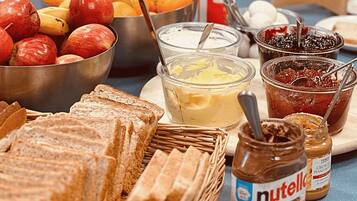 Una mesa con pan, mantequilla, mermelada y un tarro de Nutella.