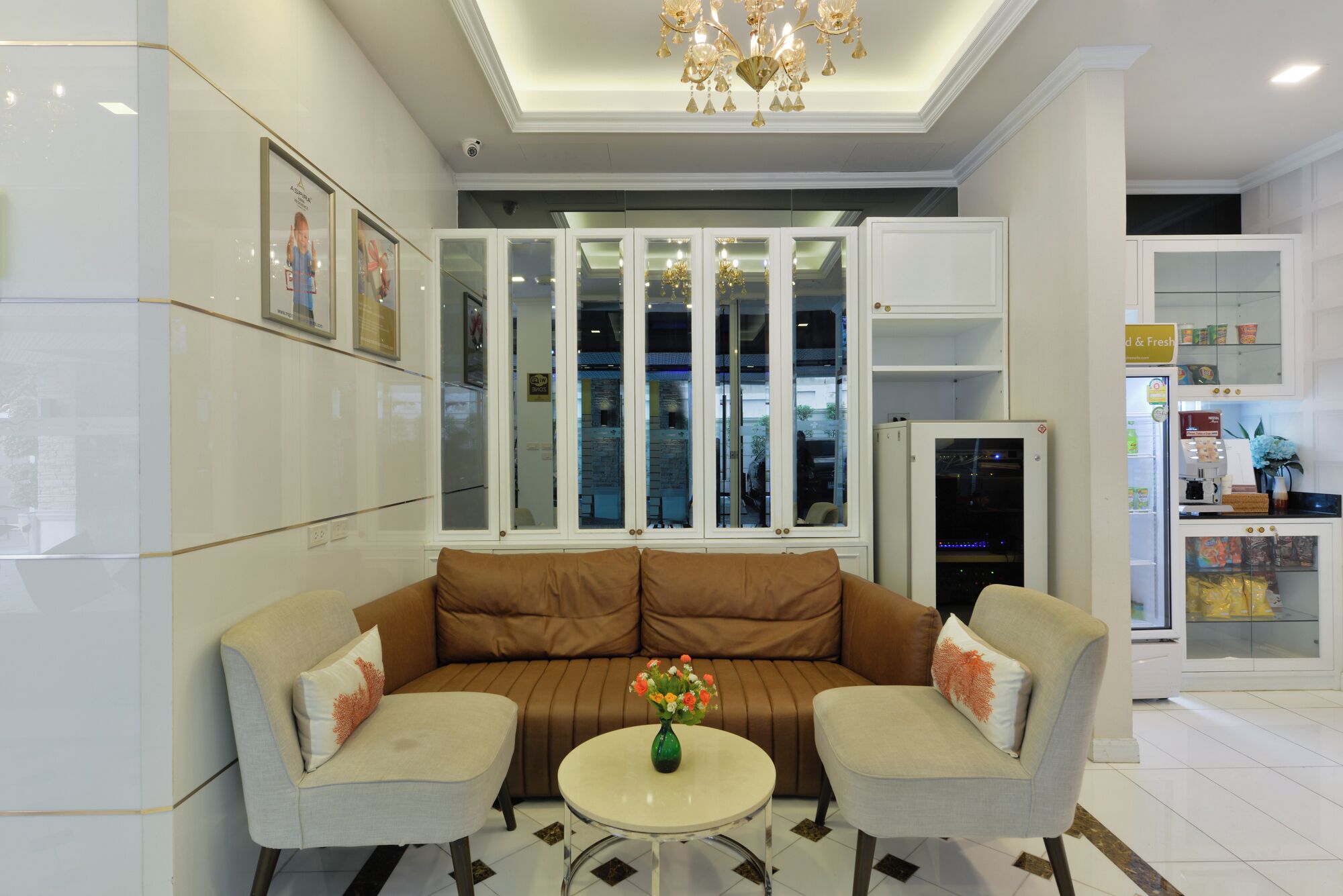 A modern living room with a brown sofa, two armchairs, and a small table with a vase of flowers.