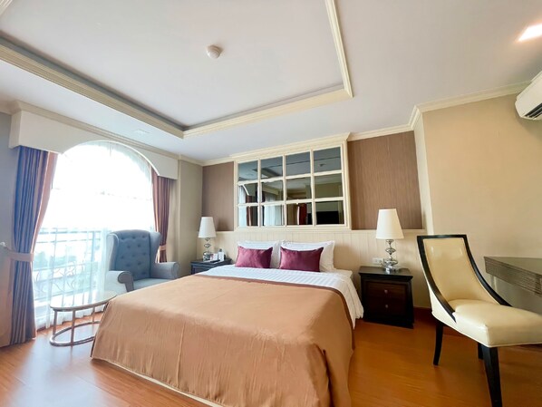 A hotel room with a large bed, two bedside tables with lamps, a chair, a window with curtains, and a balcony view. - Aspira Hana Executive Suites Thonglor (Bangkok)