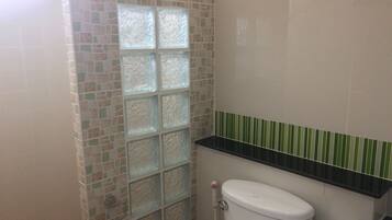 A bathroom with a tiled wall, a toilet, and a shower area.