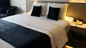 Et hotelværelse med en stor seng, to sengeborde med lamper, og en stol.
