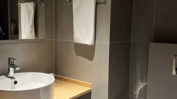 Un baño moderno con lavamanos, toallero, inodoro y un cubo de basura.