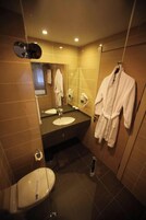 Un baño moderno con lavamanos doble, inodoro, espejo y bata colgada en la pared.