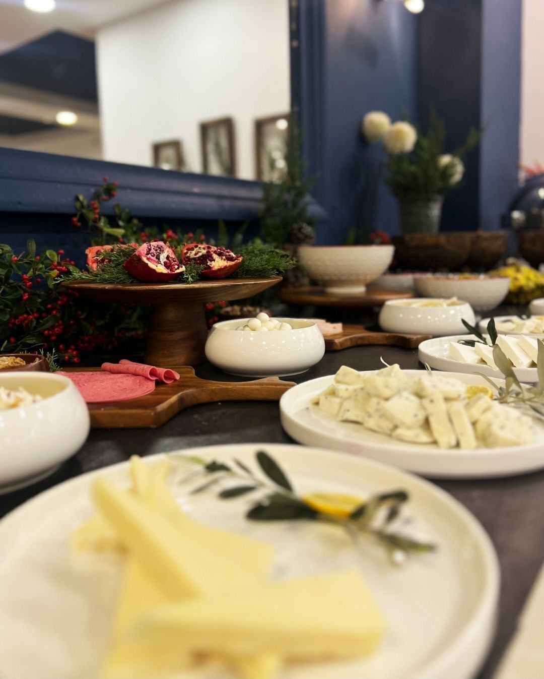 Mesa de buffet com diversos alimentos e uma decoração central com romã.