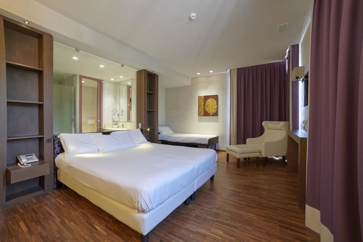 Une chambre d’hôtel avec un grand lit, deux tables de chevet, une chaise et un bureau.