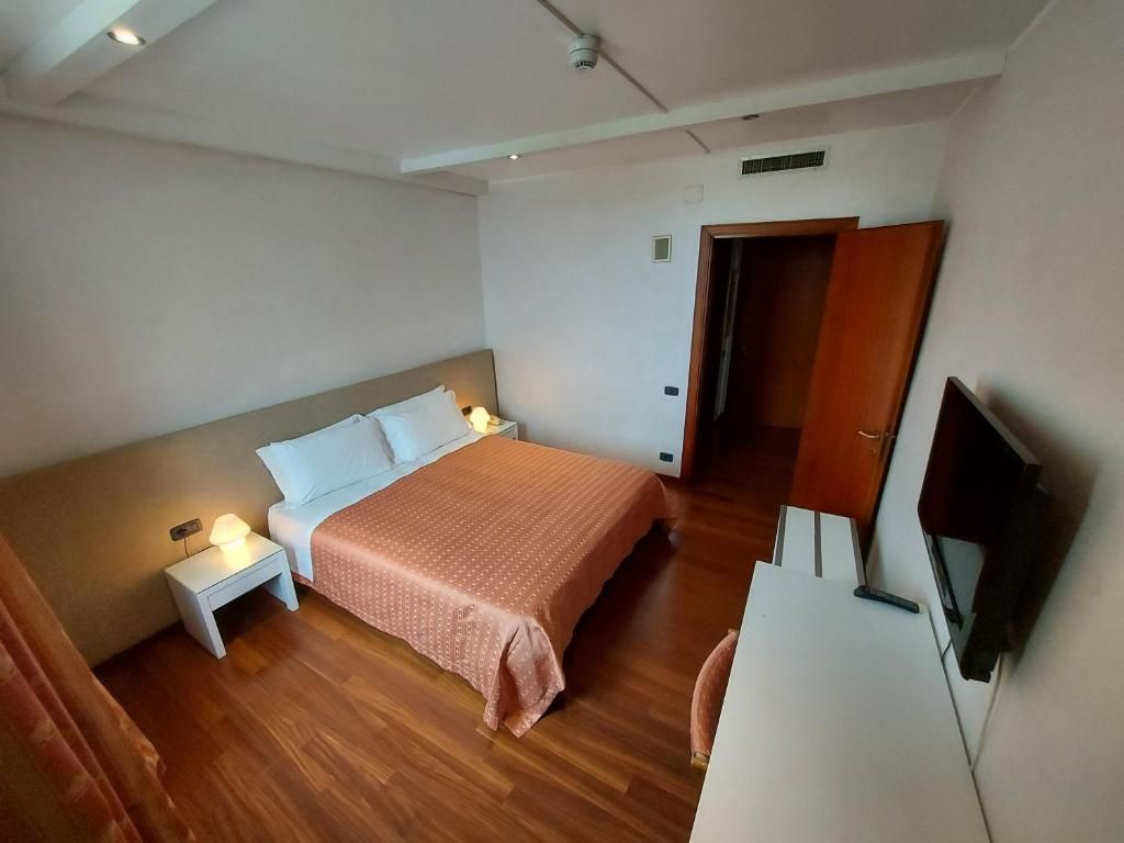Ein Schlafzimmer mit Bett, Nachttischlampen, einem Fernseher und einem Kleiderschrank.