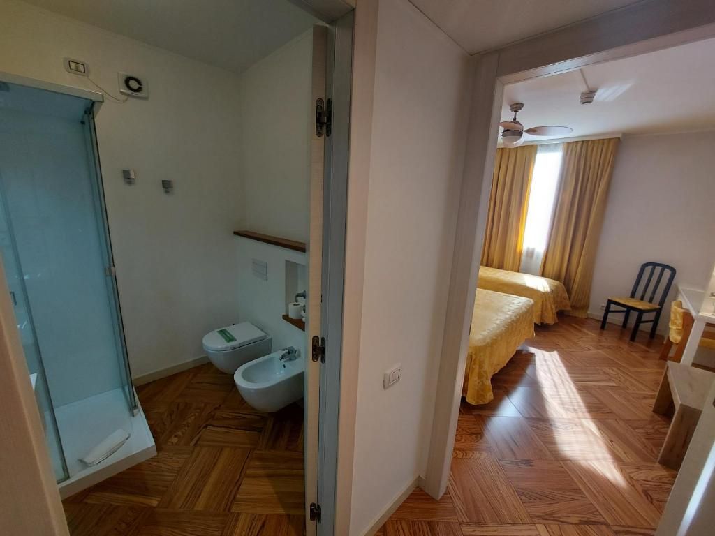 Habitación con ducha, inodoro y cama con ventilador de techo.