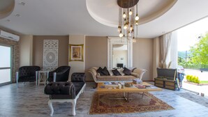 A spacious living room with a large sofa, two armchairs, a coffee table, and a decorative mirror. - Room Room Boutique Hotel (Sapanca)
