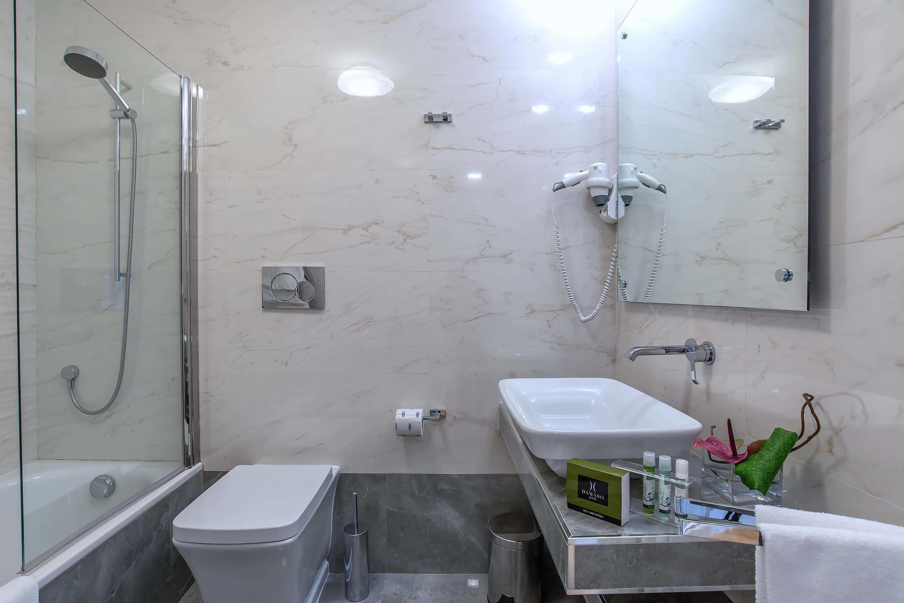 A modern bathroom with a glass-enclosed shower, a white sink, and a vanity with toiletries.