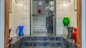 A marble staircase leading to a room with a window, a red vase, and a green vase on the landing. - Damaso Hotel (Rome)