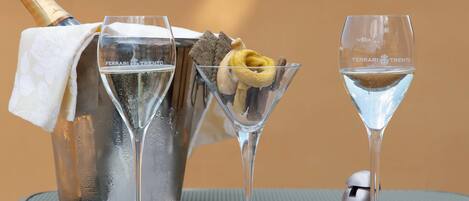 A champagne bottle, two martini glasses, and a small container with the letter "P" on a table.