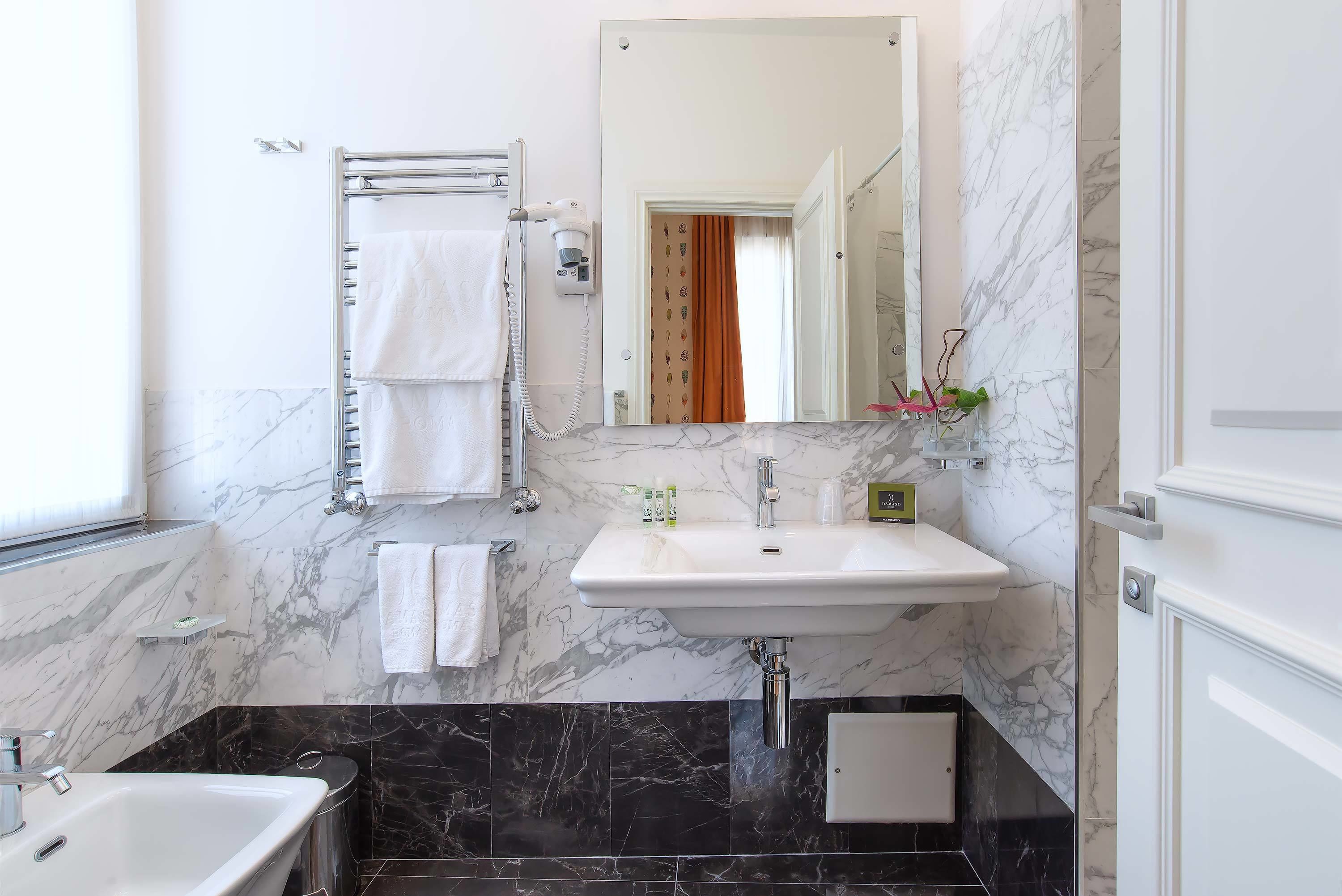 A bathroom with a marble sink, a mirror, a towel rack, and a shower area.