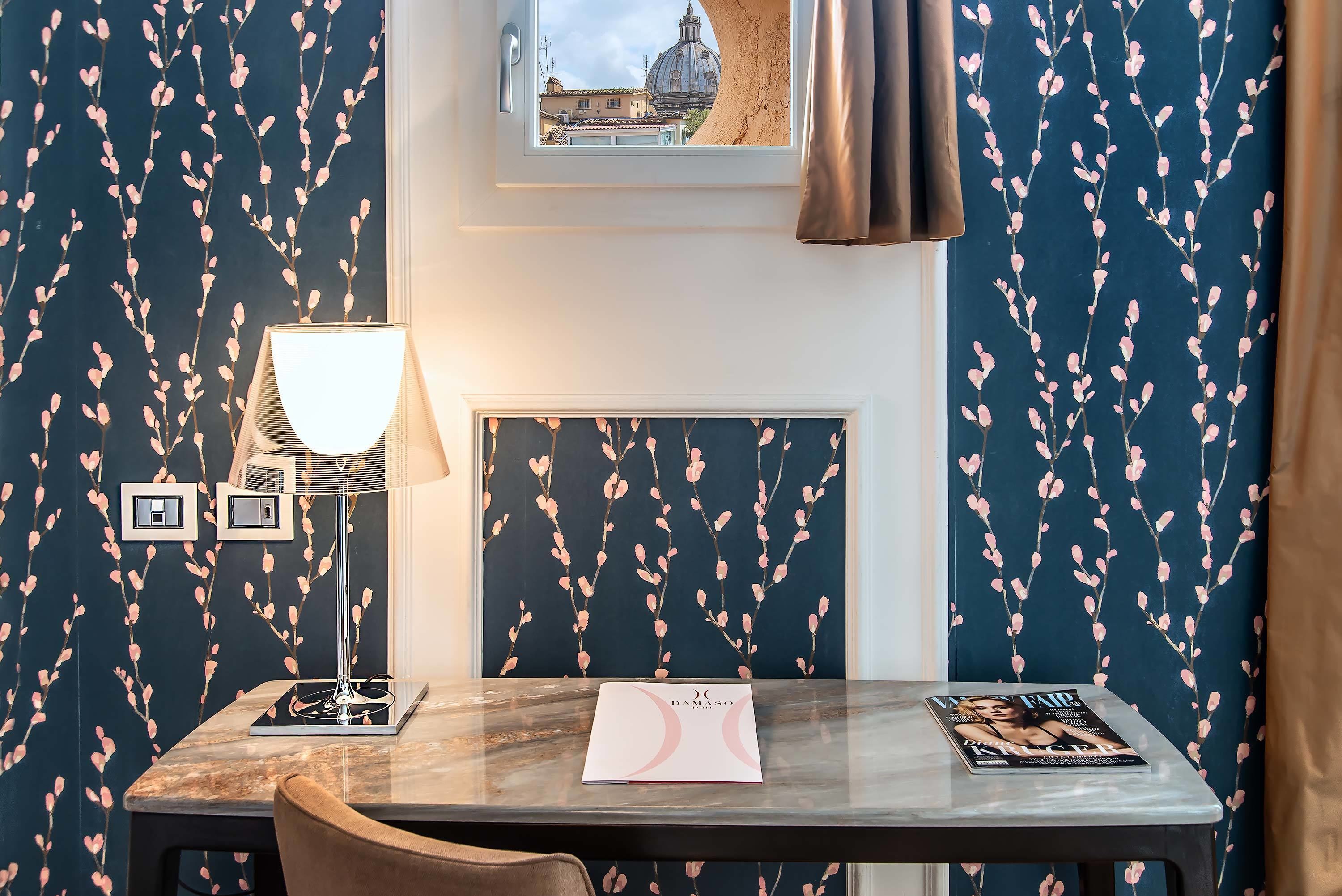 A hotel room with a marble table, a lamp, a magazine, and a framed picture on the wall.