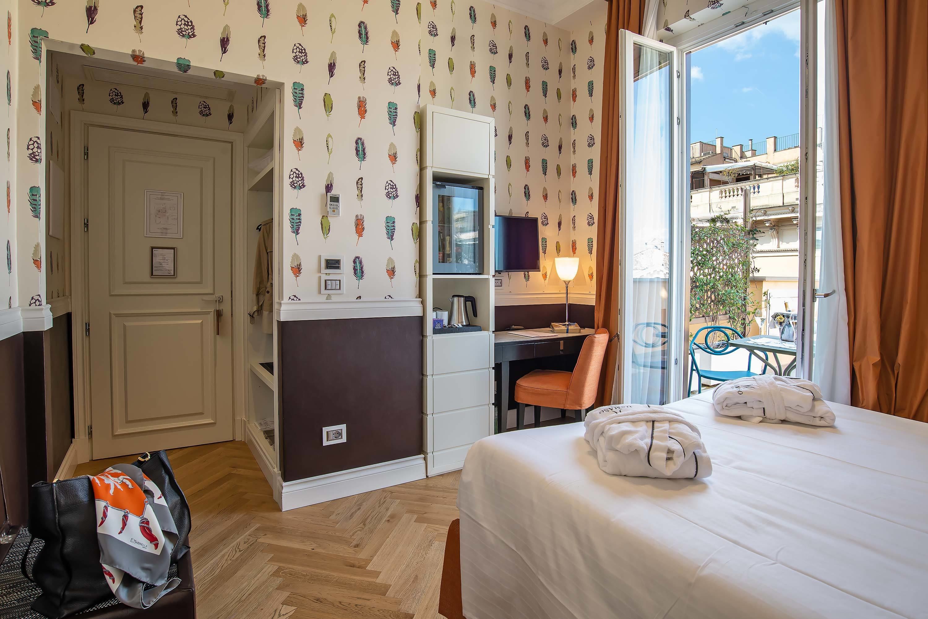 Habitación de hotel con cama, escritorio, silla, televisión y balcón con vista a la ciudad.