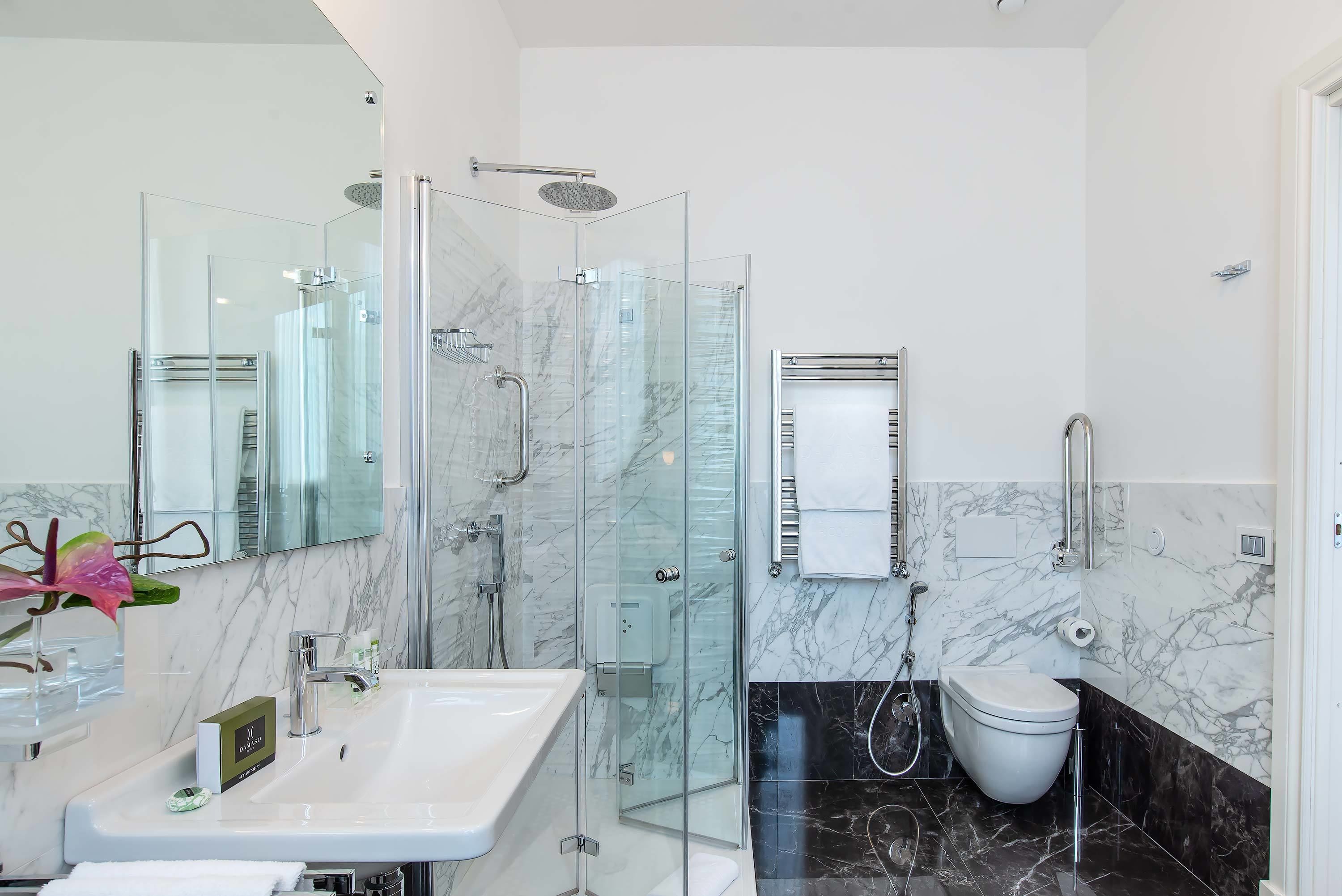 Un baño moderno con cabina de ducha de vidrio, lavamanos blanco y un inodoro.