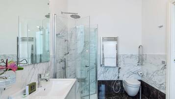 Un baño moderno con cabina de ducha de vidrio, lavamanos blanco y un inodoro.