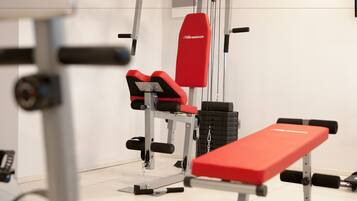 A gym with red and black equipment, including a bench and weight stacks.
