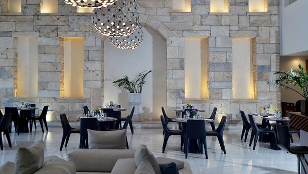 A spacious lobby with stone walls, modern lighting, and comfortable seating areas. - Athenaeum Grand Hotel (Kallithea)