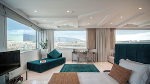 A modern hotel room with a large bed, a sofa, a desk, and a TV. - Athenaeum Grand Hotel (Kallithea)
