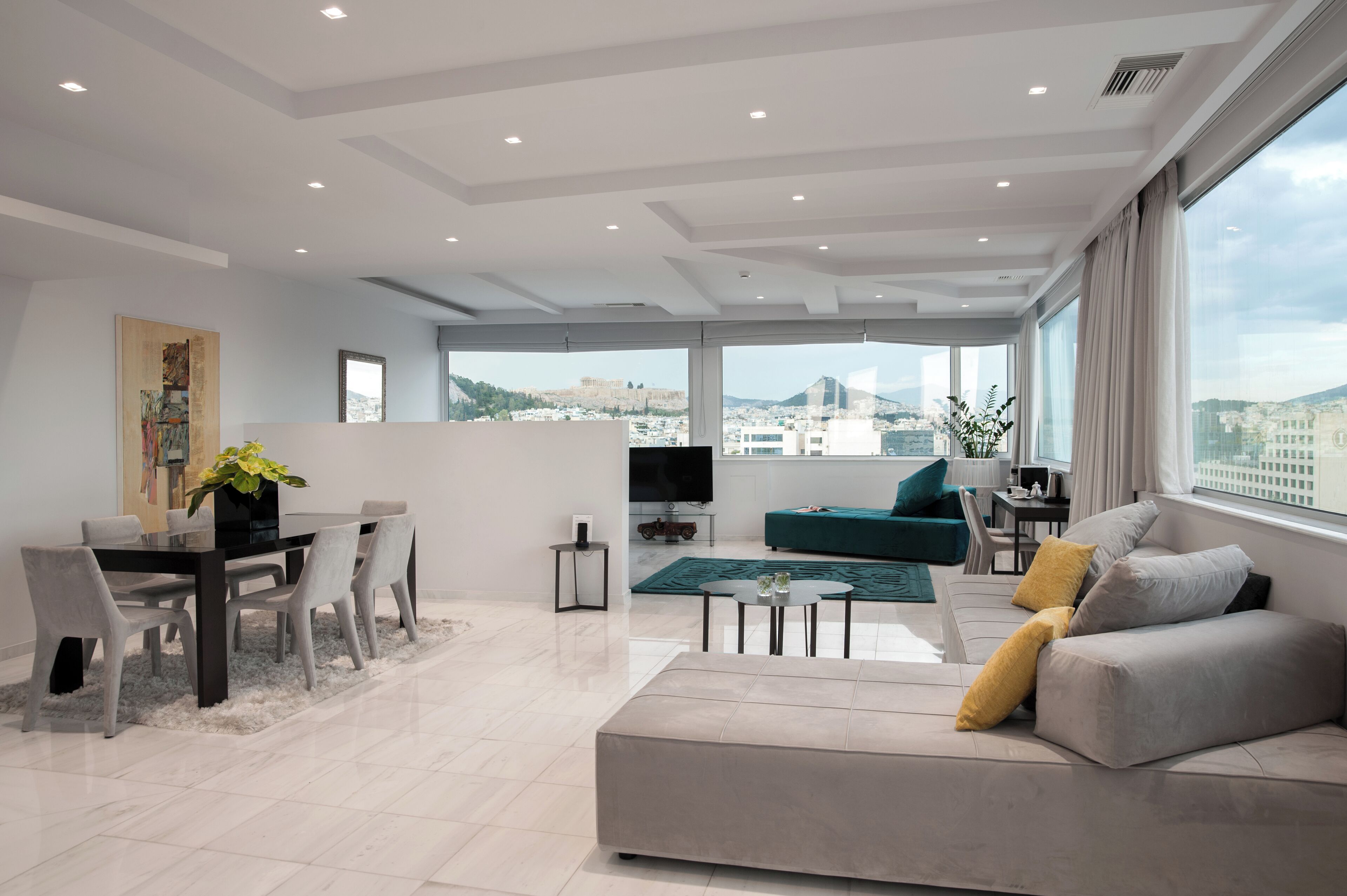 A modern living room with a sofa, a dining table with chairs, a TV, and a large window with a city view.