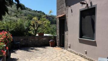 Un patio in pietra con una porta che dà su una stanza con una finestra.