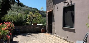 A stone patio with a door leading to a room with a window. - Podere don Peppe 1884 (Massa Lubrense)