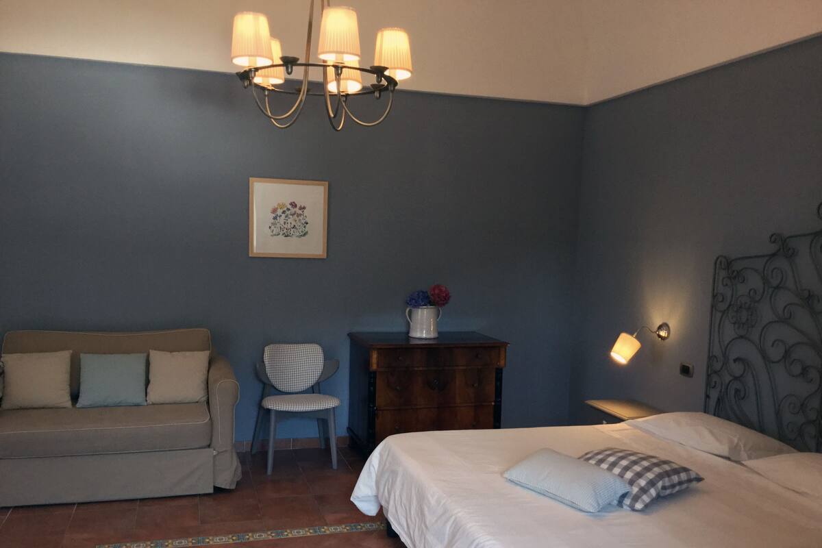 A bedroom with a bed, a chair, a dresser, and a couch.