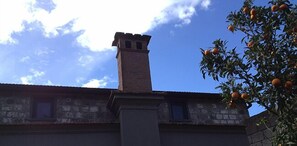A stone building with a chimney and a tree with oranges. - Podere don Peppe 1884 (Massa Lubrense)