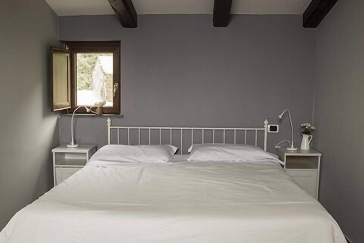 A bedroom with a bed, nightstands, a window, and a lamp.