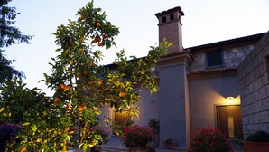 Un edificio de piedra con una chimenea de ladrillo, una planta en maceta y un parterre de flores.