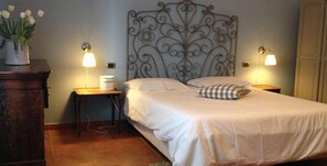 A neatly made bed with a decorative headboard, two bedside tables with lamps, and a small plant on the left side. - Podere don Peppe 1884 (Massa Lubrense)