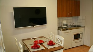 Een compacte keuken met witte kastjes, een magnetron en een koffiezetapparaat.