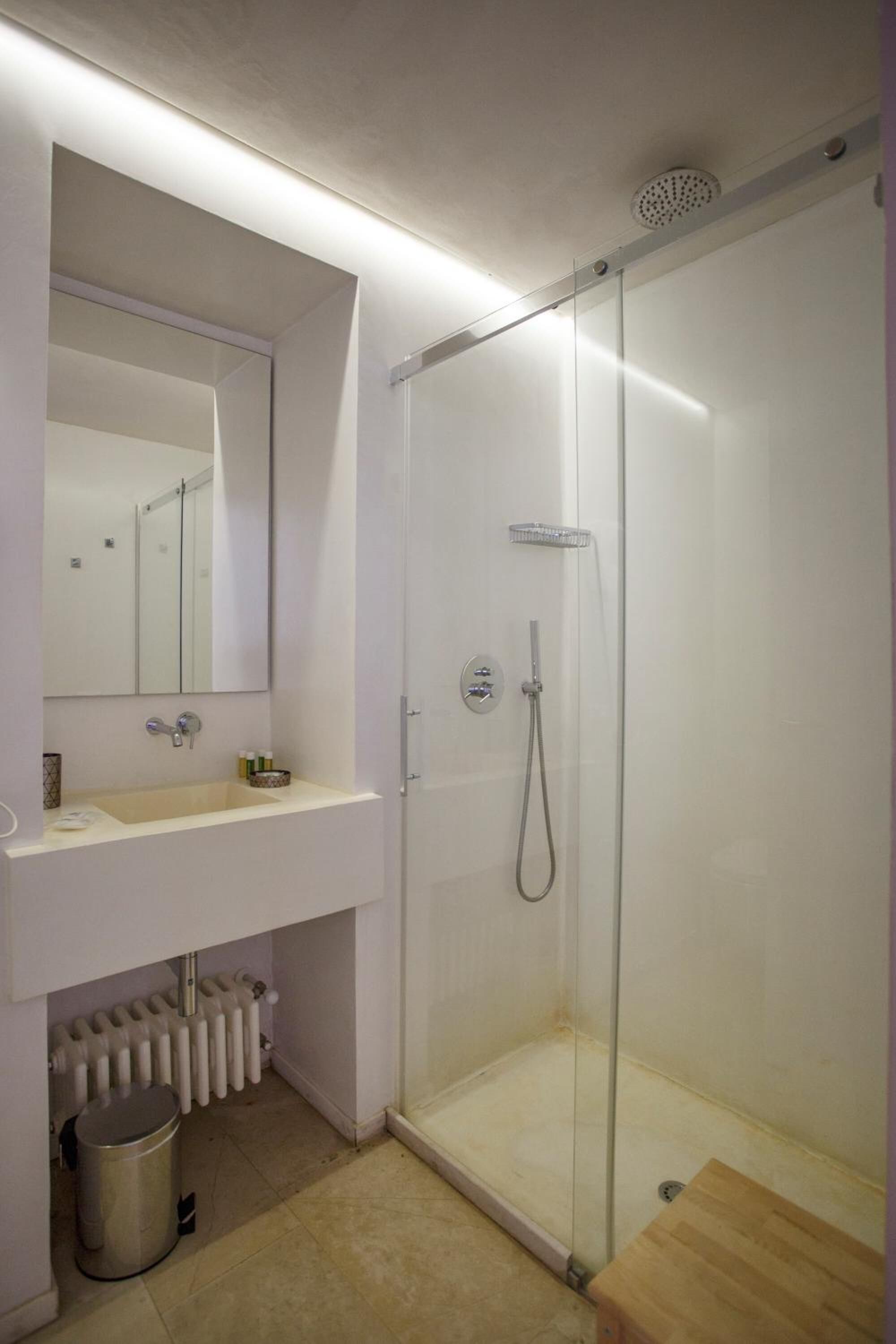 A modern bathroom with a glass-enclosed shower, a white sink, and a mirror above it.
