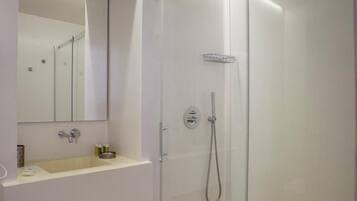 A modern bathroom with a glass-enclosed shower, a white sink, and a mirror above it.