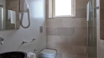 A modern bathroom with a glass shower enclosure, a bidet, and a large mirror.